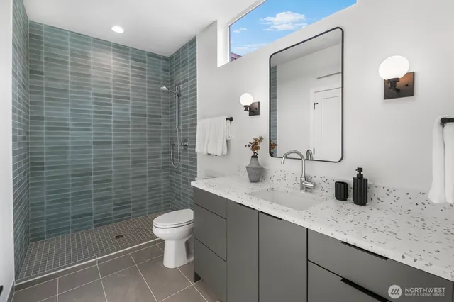 a bathroom with a granite countertop toilet sink and mirror