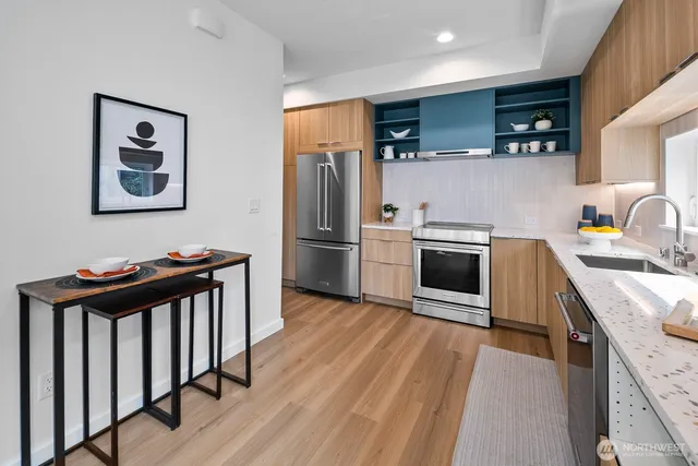 a kitchen with stainless steel appliances a stove a sink a refrigerator and wooden floor