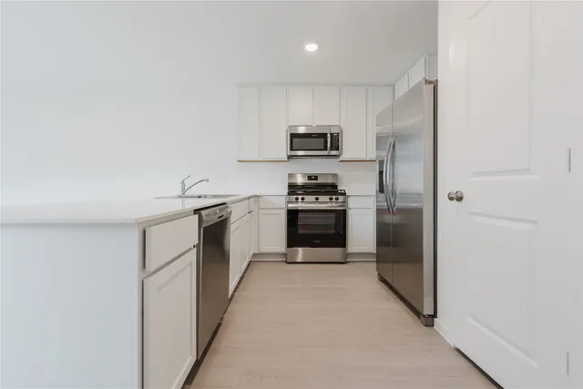 a kitchen with cabinets stainless steel appliances and sink
