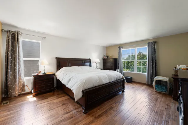 a bedroom with a bed wooden floor and window
