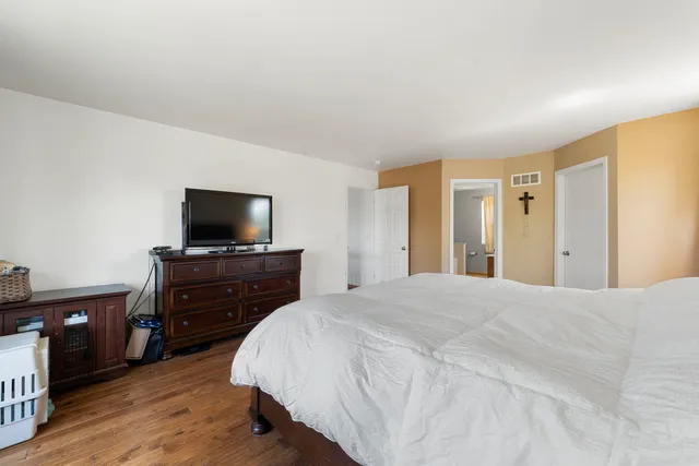 a bedroom with a bed and a flat tv screen on a dresser