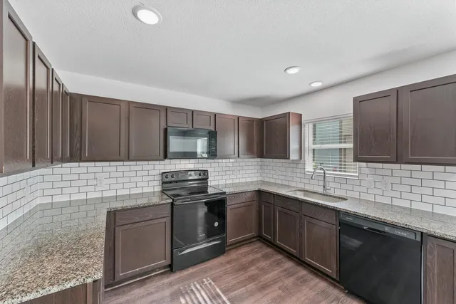 a kitchen with stainless steel appliances kitchen island granite countertop a sink stove and cabinets