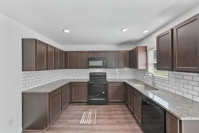 a kitchen with stainless steel appliances granite countertop a sink stove and cabinets
