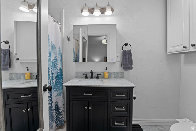 10686 South Covered Brg Cyn Road, Unit 14 Spanish Fork, UT 84660 - Photo 41 of 44 Bathroom vanity featuring a black cabinet with silver hardware, a light-toned countertop, and a recessed medicine cabinet with integrated lighting