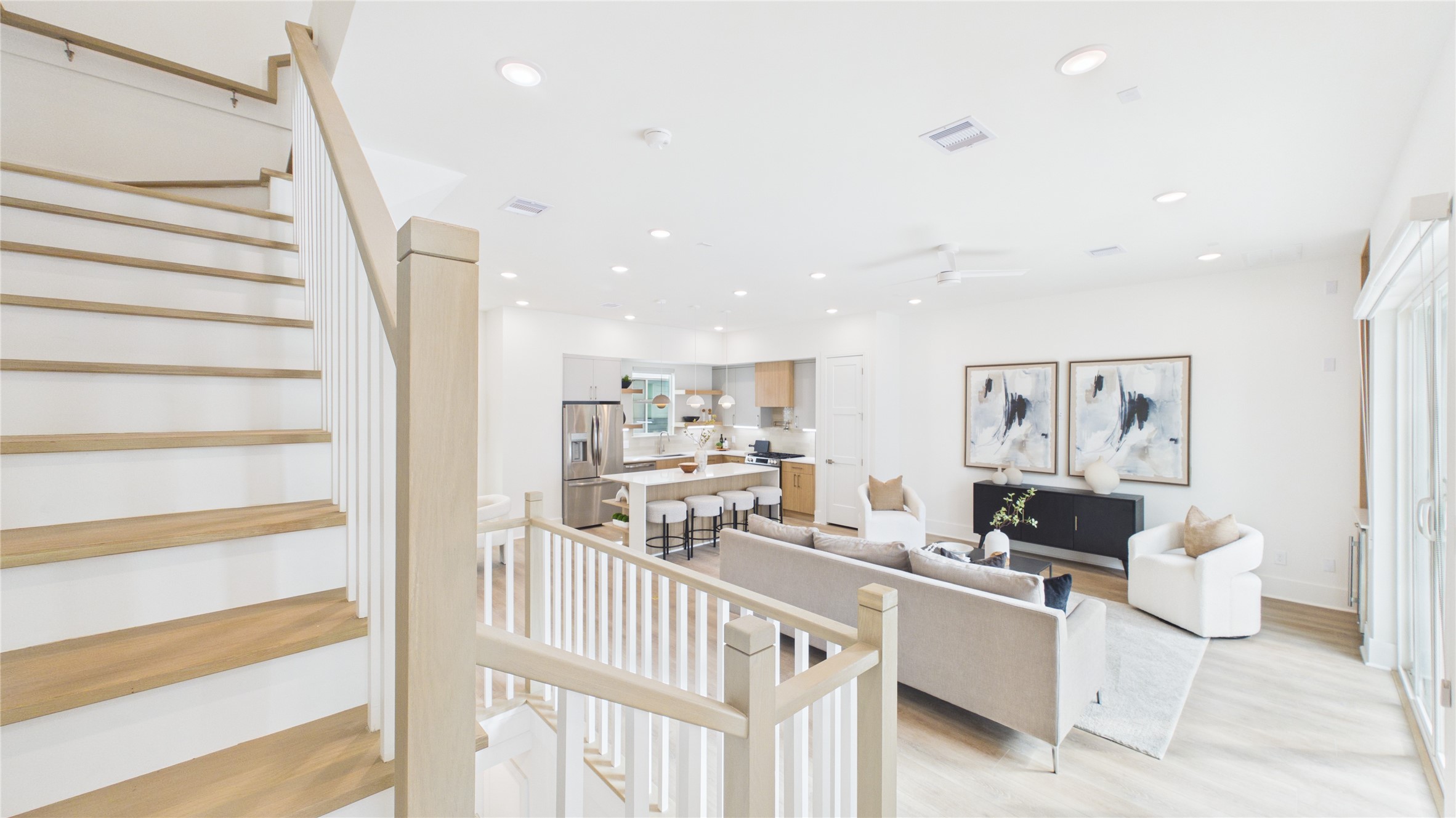 602 Skyland Terrace Way Houston, TX 77009 - Photo 13 of 40 This modern, open-concept living space features a bright, airy design with light wood flooring, a stylish kitchen with stainless steel appliances, and comfortable seating. The staircase adds elegance, while large windows ensure plenty of natural light.