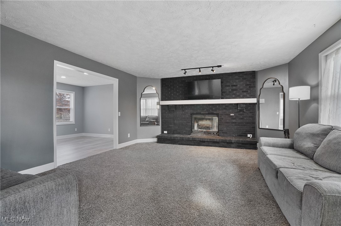 9278 Bryant Road Windham, OH 44288 - Photo 2 of 47 Living area with a textured ceiling, a brick fireplace, carpet flooring, and track lighting