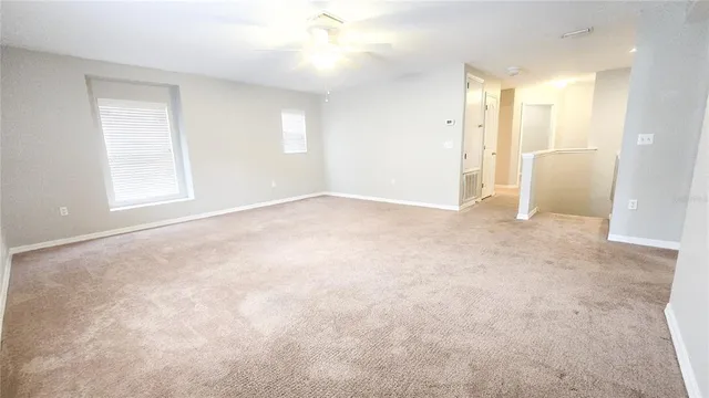 an empty room with windows and fan