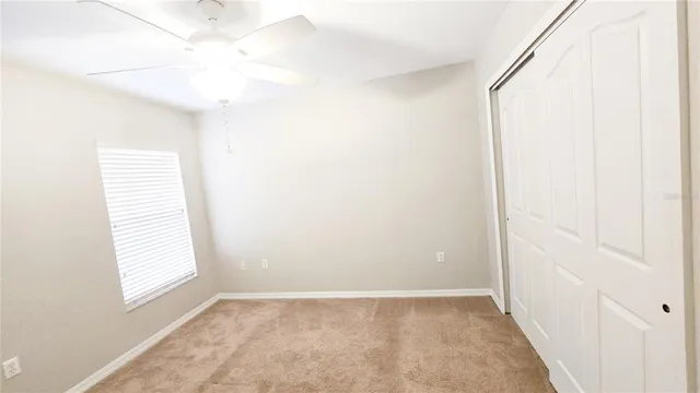 an empty room with a window and a ceiling fan