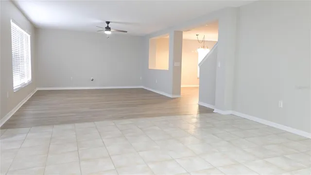 an empty room with windows and ceiling fan