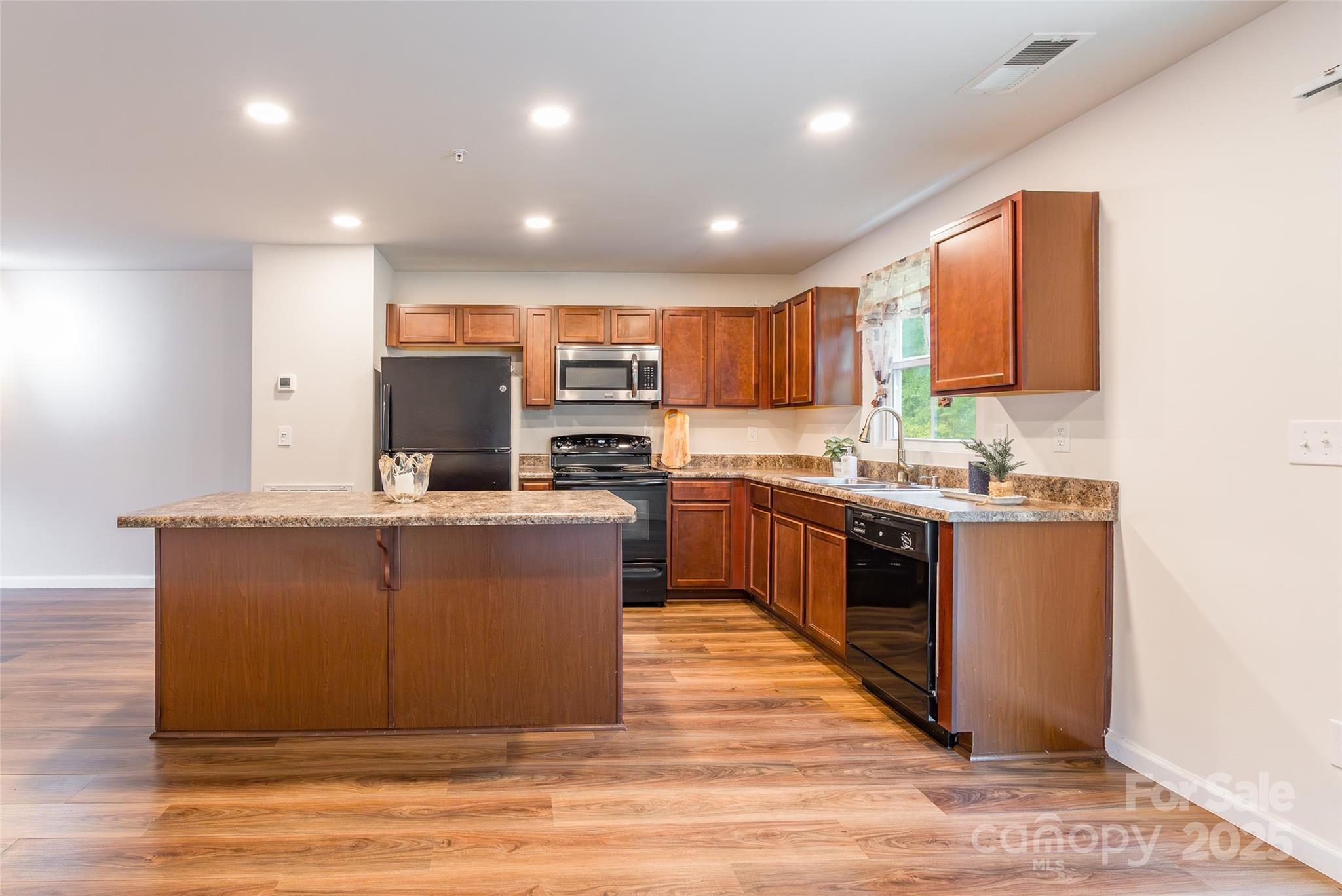 1128 Tangle Ridge Drive Southeast Concord, NC 28025 - Photo 5 of 27 a kitchen with kitchen island a sink wooden floor and stainless steel appliances
