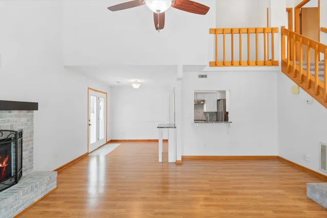 a view of an empty room with wooden floor fireplace and a window