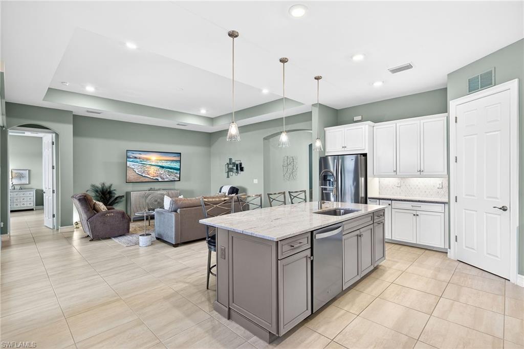 14523 Kelson Circle Naples, FL 34114 - Photo 13 of 50 a large kitchen with kitchen island a stove a sink a center island a dining table and chairs