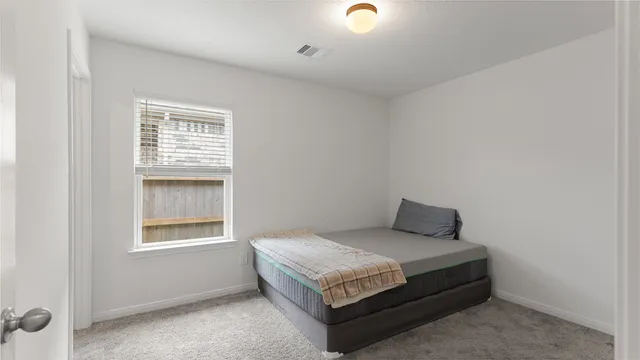 a bed sitting in a bedroom next to a window