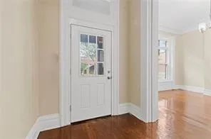 an empty room with wooden floor closet and windows