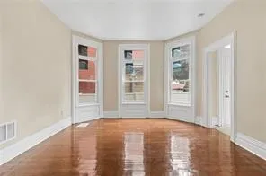 a view of an empty room with window and wooden floor