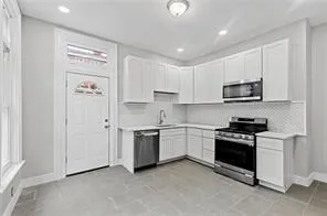 a kitchen with granite countertop white cabinets and stainless steel appliances