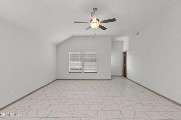 an empty room with chandelier fan and windows