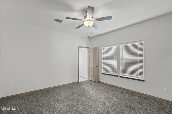 an empty room with windows and fan