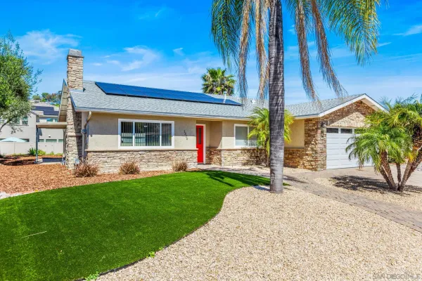 a view of a house with a yard and palm trees