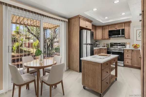a kitchen with stainless steel appliances a stove a sink a refrigerator and a dining table