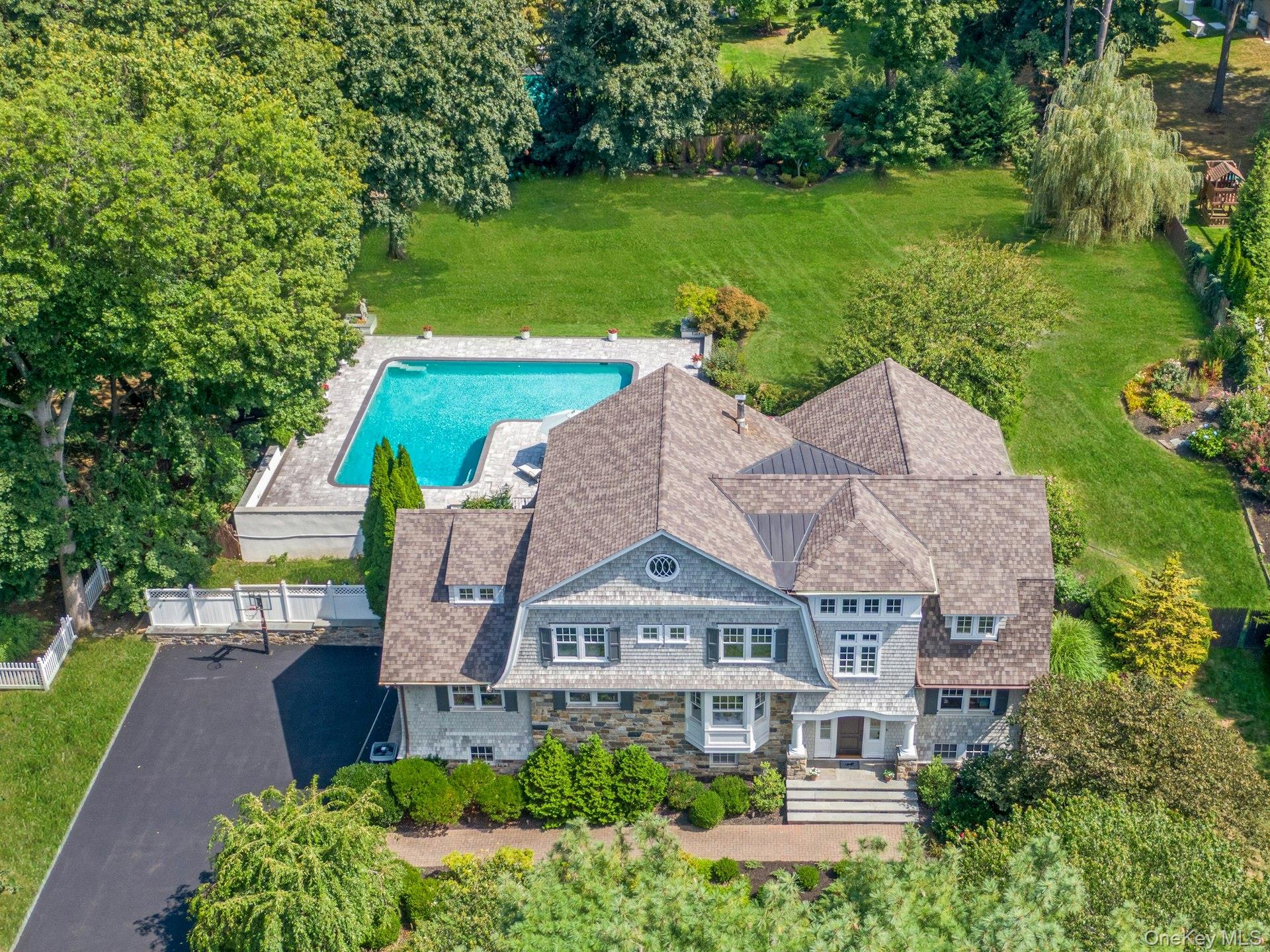 Aerial view of this exceptional, fully renovated Dutch Colonial set on .9 acres of expansive, level grounds, highlighting the home’s impressive scale, distinguished architectural significance, elevated finishes, and resort style pool. Thoughtfully transformed by renowned architect Miguel Sostre and expertly executed by prominent local builder Paul Fonatana of Cum Laude Group.