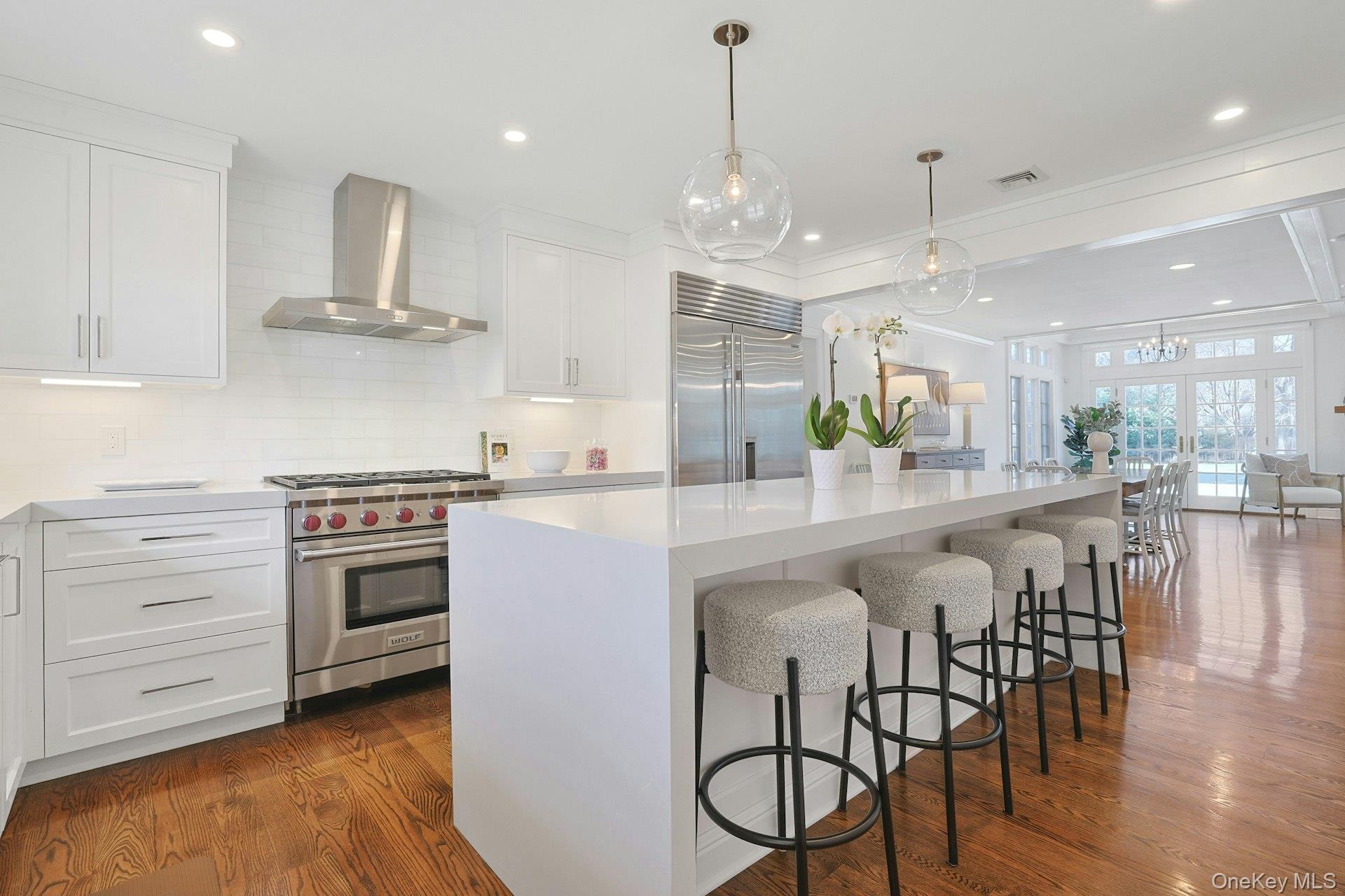 369 Evandale Road Scarsdale, NY 10583 - Photo 13 of 49 Chef’s kitchen, renovated in 2022, features a Wolf 6-burner gas range with professional hood, 48" Sub-Zero refrigerator/freezer, extra thick quartz countertops with a waterfall island, dolomite backsplash, Bosch dishwasher, built-in microwave and convection oven, ample cabinetry, pantry storage, and a custom spice cabinet.