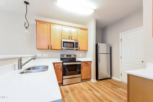 a kitchen with stainless steel appliances granite countertop a sink a stove a refrigerator with white cabinets and wooden floor