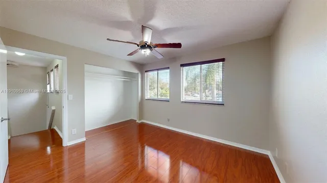 a view of empty room with wooden floor and fan