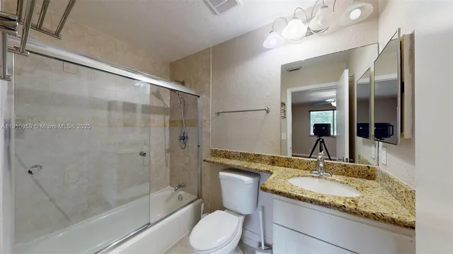 a bathroom with a granite countertop sink toilet and shower