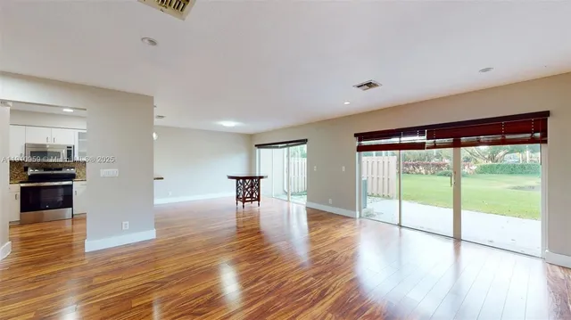 a view of empty room with wooden floor and floor to ceiling window