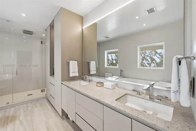 a bathroom with double vanity sinks a shower and a mirror
