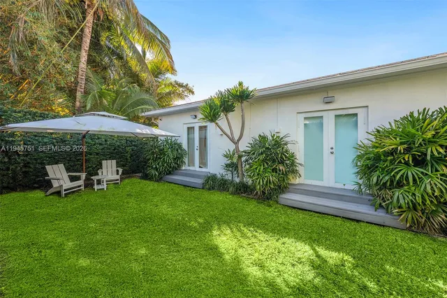 a view of a chair and table under an umbrella in front of house
