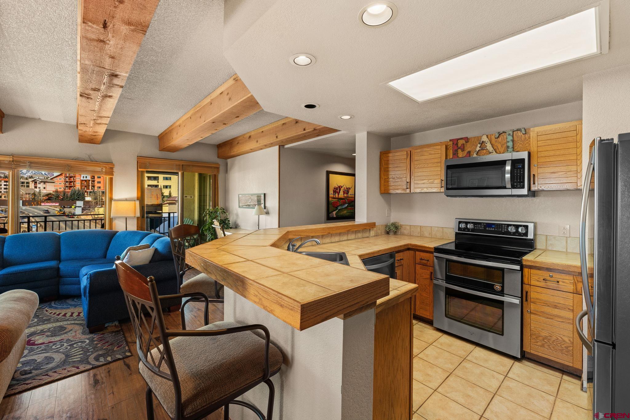 11 Snowmass Road, Unit 638 Crested Butte, CO 81225 - Photo 23 of 41 a kitchen with stainless steel appliances granite countertop a stove a sink dishwasher and a refrigerator with wooden floor