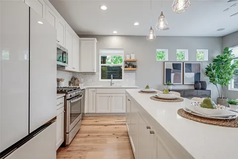 a kitchen with kitchen island a stove a sink a refrigerator and cabinets