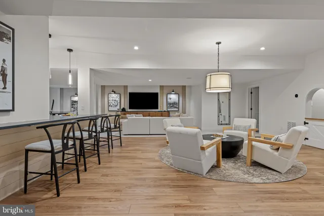 a living room with couches chairs and a dining table with wooden floor