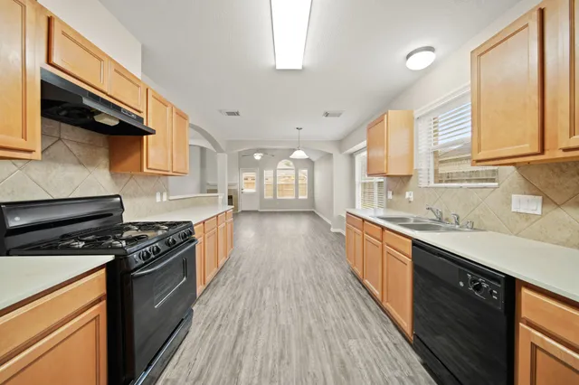a large kitchen with kitchen island a large counter top space a sink stainless steel appliances and cabinets