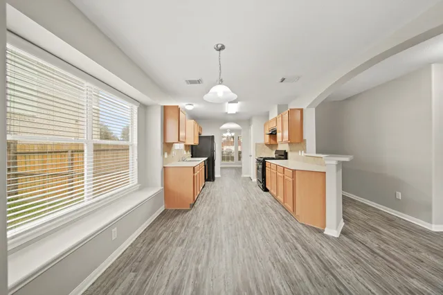 an empty room with windows fireplace and a ceiling fan