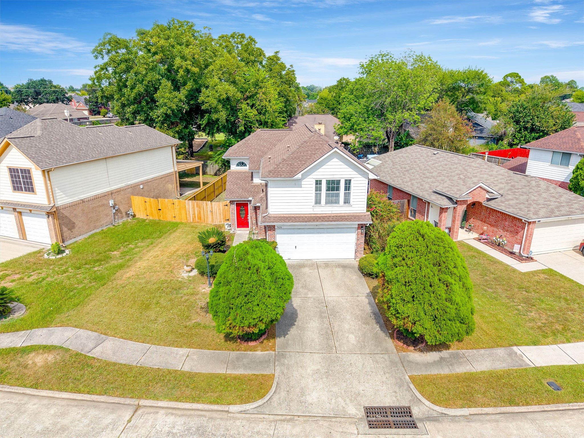 5426 Bourgeois Road Houston, TX 77066 - Photo 35 of 43 Nice two-story home with a welcoming red door, nestled between lush green bushes and featuring a spacious driveway. Perfectly situated in a peaceful neighborhood with mature trees providing ample shade.