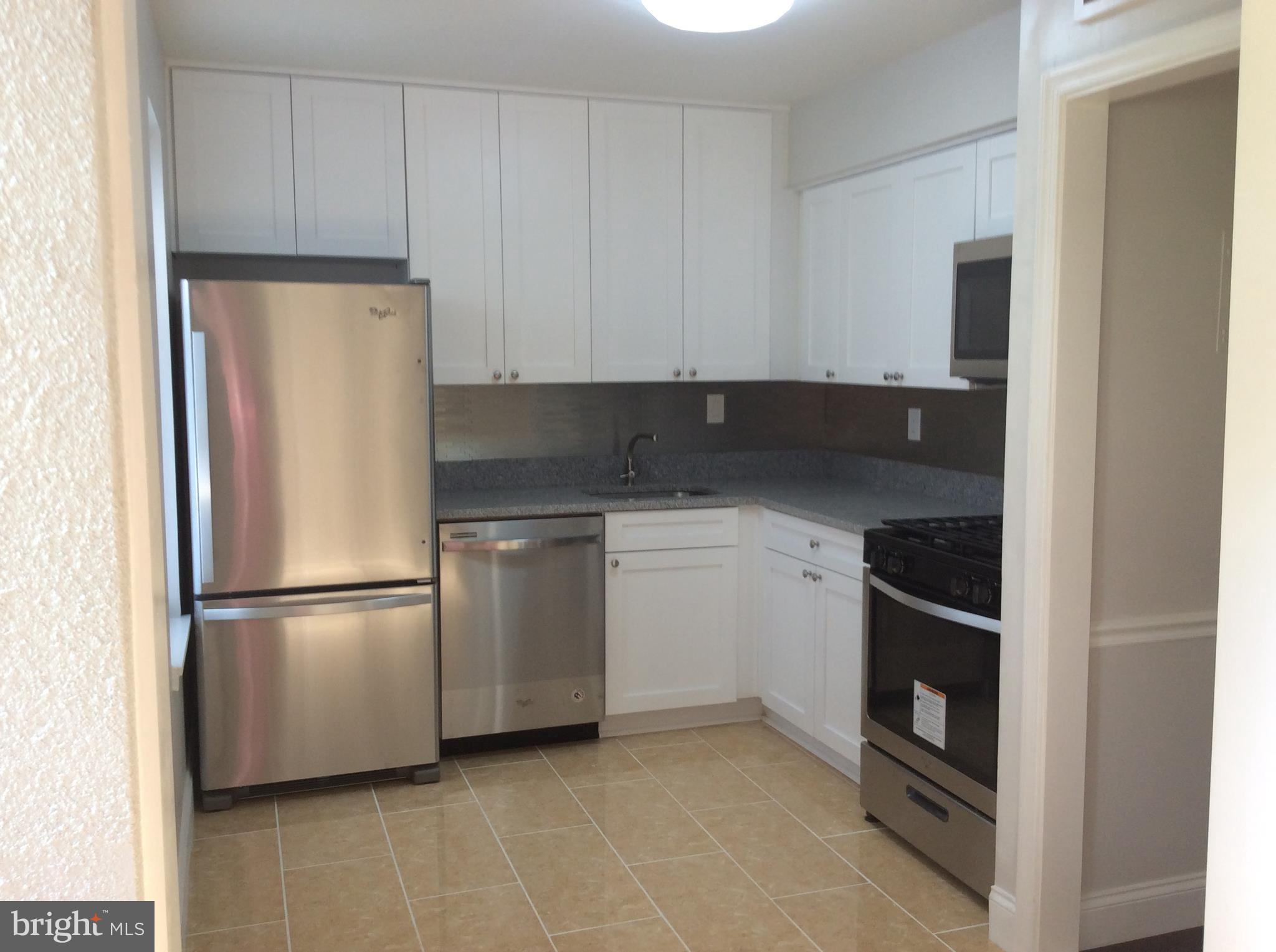 9633 White Acre Road, Unit A2 Columbia, MD 21045 - Photo 16 of 27 a kitchen with white cabinets and refrigerator