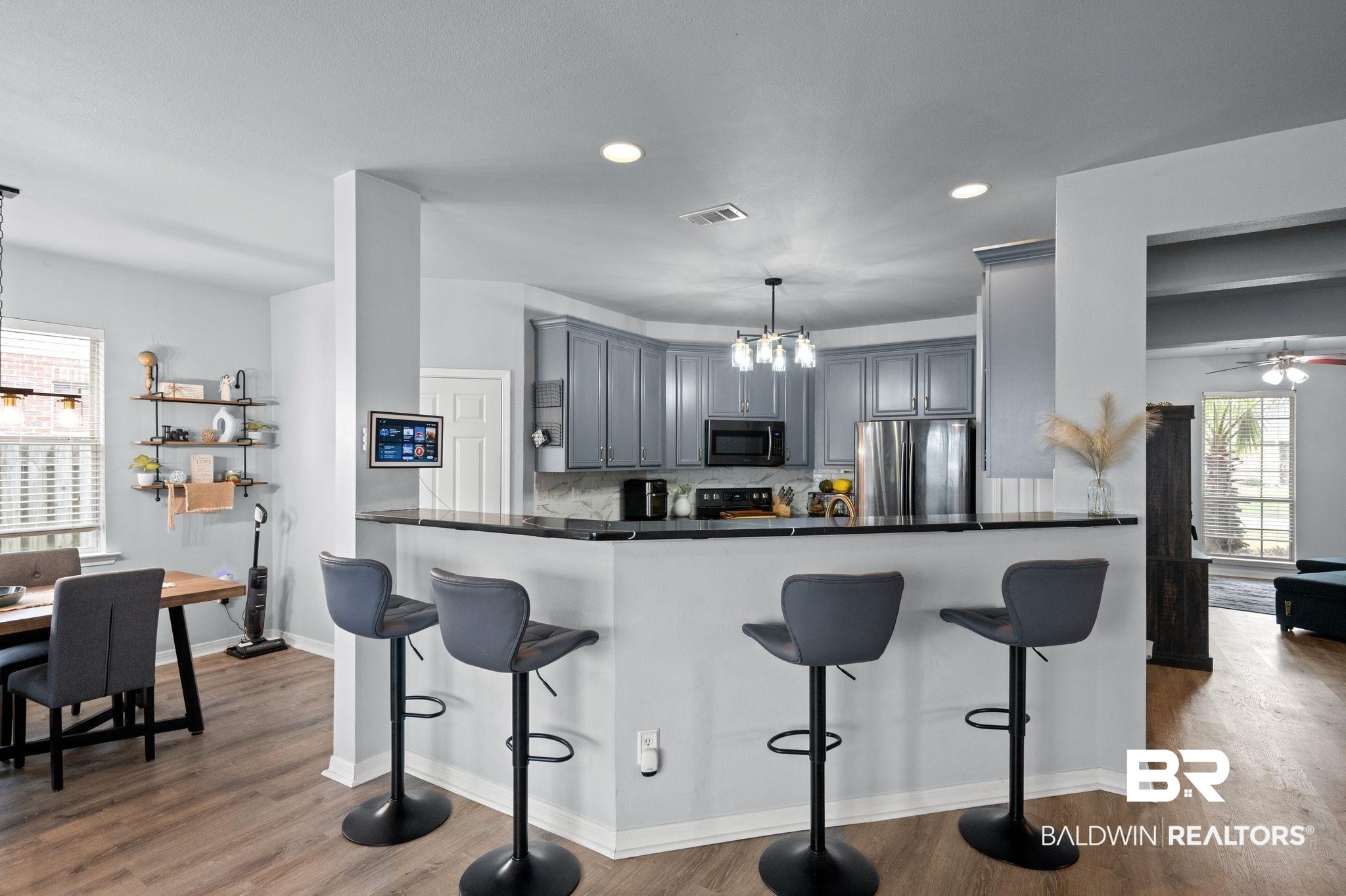 1287 Pembroke Way Foley, AL 36535 - Photo 15 of 39 Kitchen with suspended lighting, gray cabinetry, stainless steel appliances, a kitchen bar, and dark wood-type flooring
