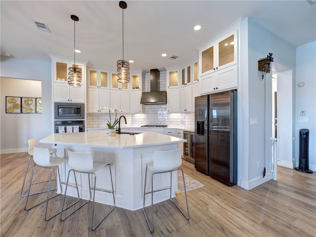 16101 Jessamine Street Corpus Christi, TX 78418 - Photo 4 of 28 a kitchen with stainless steel appliances granite countertop a refrigerator a sink dishwasher a stove and white cabinets with wooden floor