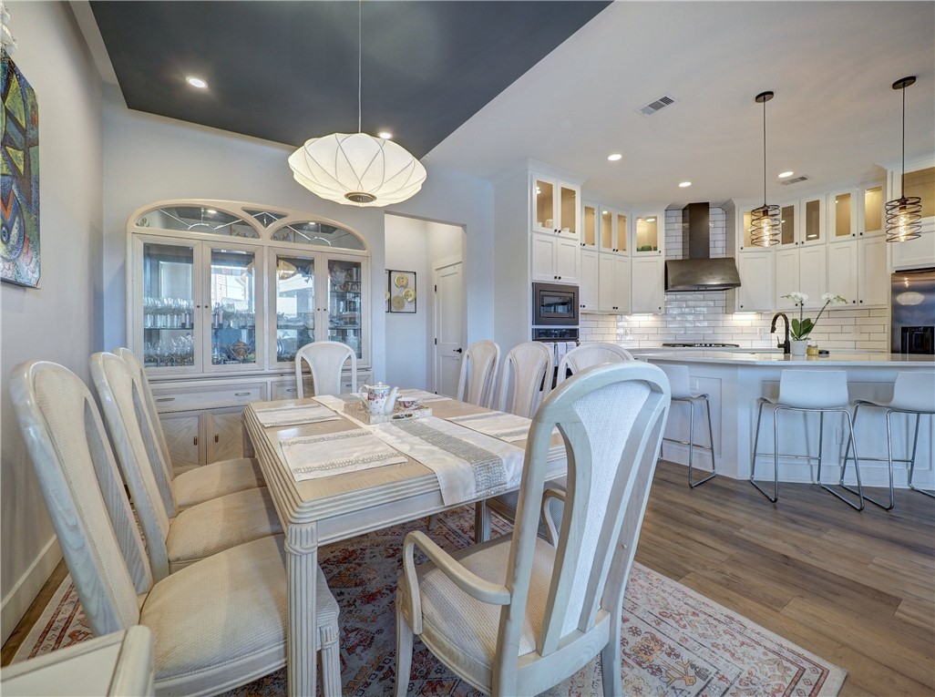 16101 Jessamine Street Corpus Christi, TX 78418 - Photo 6 of 28 a dining room with wooden floor a chandelier a wooden table and chairs