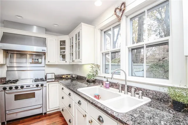 a kitchen with granite countertop a sink stove and cabinets