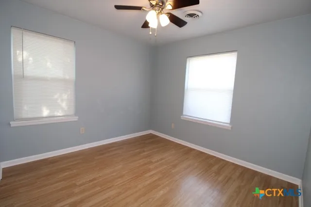 a view of an empty room with wooden floor and a window