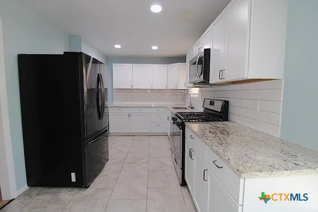 a kitchen with granite countertop a refrigerator and a sink