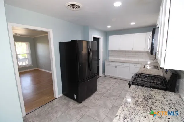 a kitchen with stainless steel appliances granite countertop a refrigerator and a stove top oven