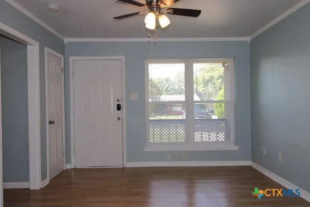 a view of an empty room with wooden floor and a window