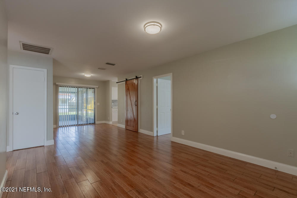 7447 Wheat Road Jacksonville, FL 32244 - Photo 7 of 42 a view of an empty room with wooden floor and a window