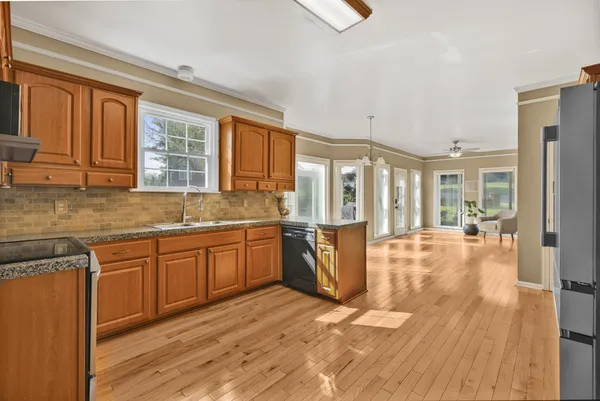 a large kitchen with kitchen island granite countertop wooden floors and wide window