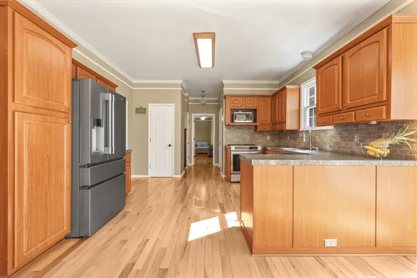 a kitchen with stainless steel appliances granite countertop a refrigerator a stove and a sink with wooden floor